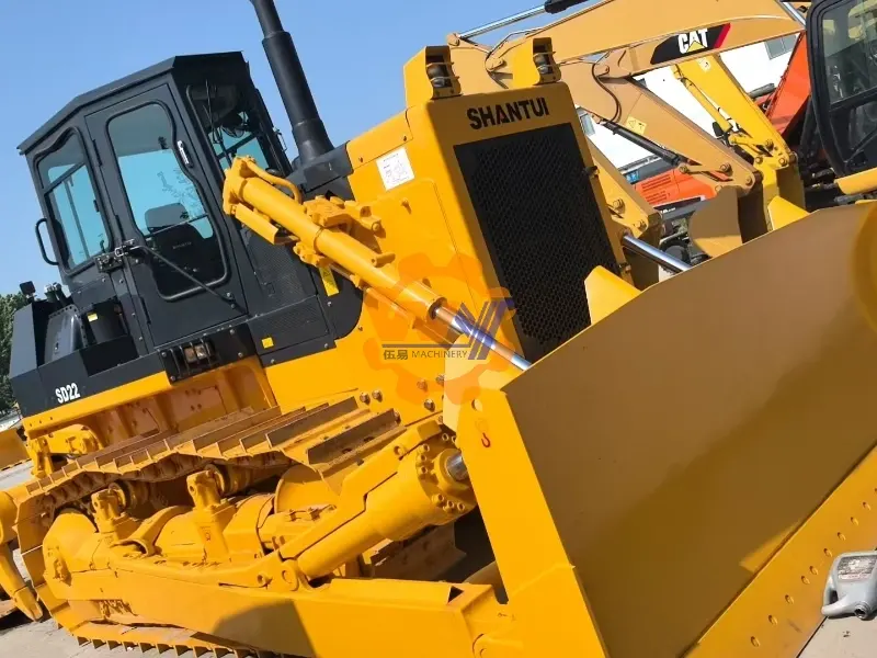 Shantui SD22 bulldozer equipped with a rear ripper and front guard for heavy-duty land clearing.